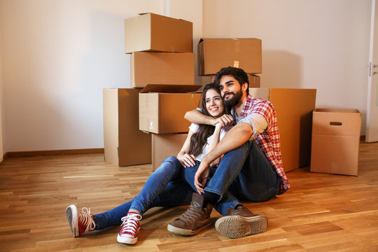 Young couple moving into a  new home.Sitting on floor in empty apartment .Real estate concept.