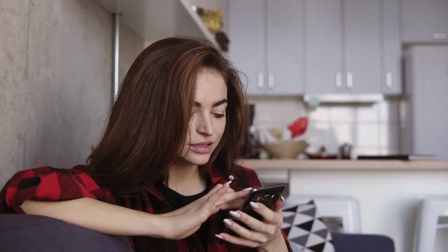 Sexy attractive young female with fancy manicure scrolling and typing something on smartphone.