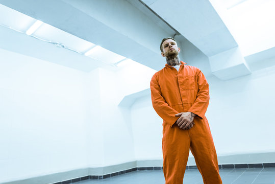 bottom view of tattooed criminal standing in prison cell