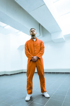 bottom view of tattooed prisoner standing in prison cell