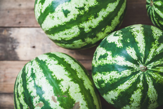 group of striped watermelons lies on wooden boards