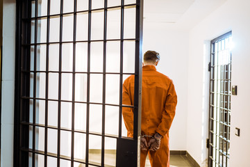 back view of prisoner standing in handcuffs in corridor - obrazy, fototapety, plakaty
