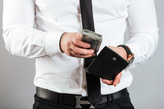 Close up of a man putting cash in his wallet