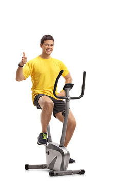 Young man exercising on a cross-trainer machine and making a thumb up gesture