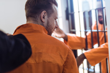 cropped image of prison guard leading criminal