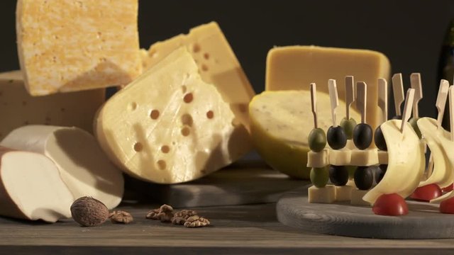 Cheese and wine tasting. Different types of cheese wedges, cheese skewered appetizers, and glasses with red wine on wooden table. Dolly shot