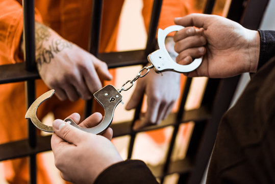 cropped image of prison officer wearing handcuffs on prisoner