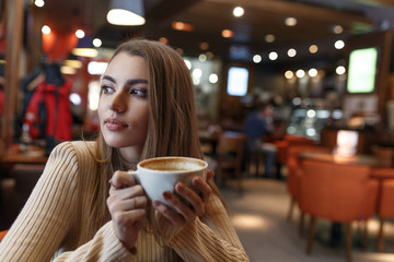 Young beautiful girl with a cup of drinks at a coffee house