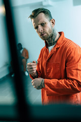 prisoner looking at camera behind prison bars