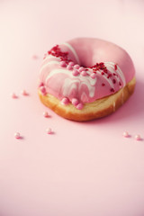 Sweet doughnut with pink icing on pastel background. Tasty donut on pink texture, copy space, top view