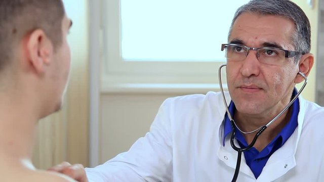 Doctor Listening To Heartbeat Of Young Man