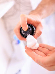 The man squeezes the shaving foam into his hand