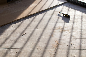 Oak colored parquet during installation on an old stoneware floor near an open window. Grazing light in the morning during the renovation of an apartment