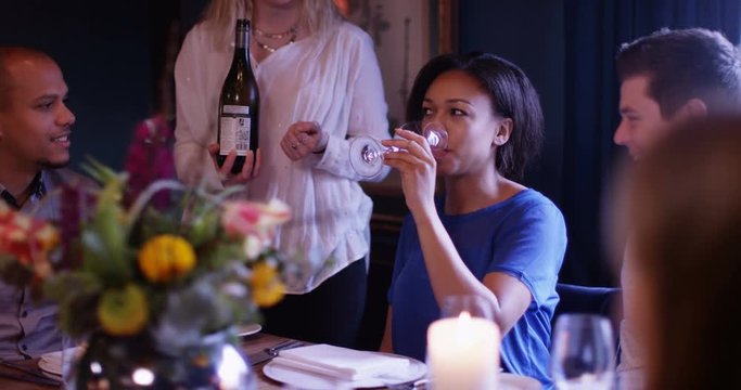 4K Cheerful waitress serves wine to adult family group in friendly restaurant
