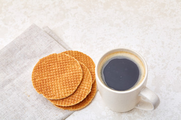 Close-up white cup of coffee with waffles on white background, top view