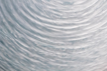 circular wave motion in a fluid system. blue gray background for a liquid pushed into a circular...