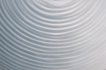 Fototapeta na wymiar circular wave motion in a fluid system. blue gray background for a liquid pushed into a circular motion. waves and concentric circles with ripples as abstract and generic background. simulation of flu