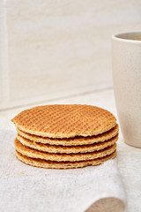 Close-up white cup of coffee with waffles on white background, top view