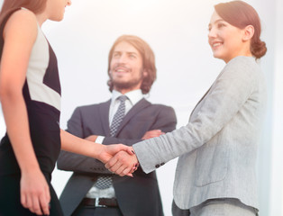 Businesspeople  shaking hands against room with large window loo
