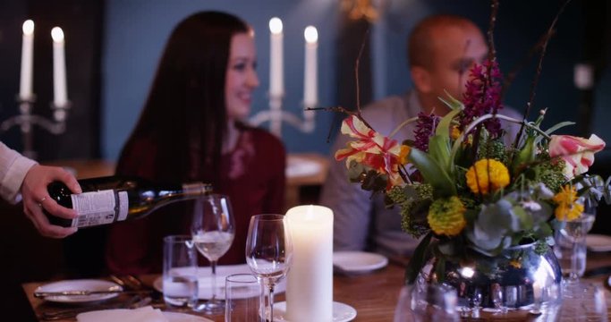 4K Waitress serves wine to adult family group in friendly restaurant