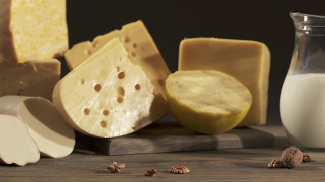 Cheese varieties. Different types of cheeses with milk jug on wooden table. Dolly shot