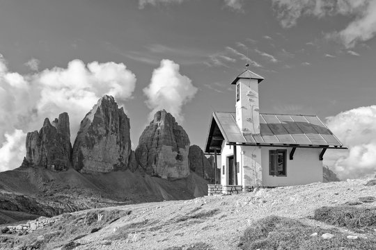 Fototapeta Die berühmten Drei Zinnen in den Sextener Dolomiten mit einer Kapelle im Vordergrund in Schwarz-Weiß, Pustertal, Südtirol, Italien
