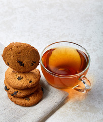 Top view closeup picture of tea in transparent cup with cookies and cotton napkin on white background, selective focus