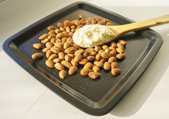 Almond flour in a wooden spoon on a background of nuts almonds.