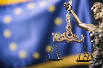 Scales of Justice, Justitia, Lady Justice in front of the European Union flag in the background.