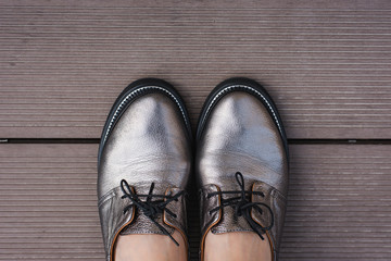 Stylish women's leather shoes with laces on a wooden board, contrasting objects
