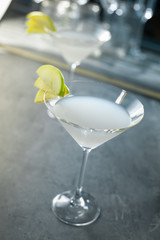  cocktail  appletini in a glass decorated with apples on a gray table with glasses in the background