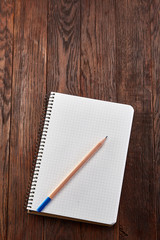 White checked copybook with pencil on pine brown wooden board