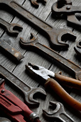 Fototapeta premium Dirty set of hand tools on a wooden background. Old rusty tools Sales tools for assembly workers. Old shop Old working. Vintage working tools (drill, saw, ruler and others) on wooden background