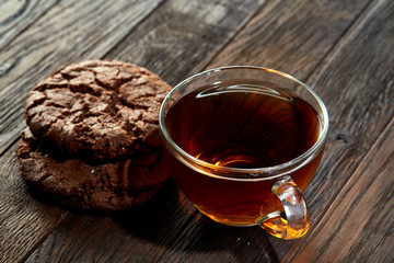 Cup of tea with cookies on a cutting board on a wooden background, top view