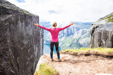 Young woman hiking on kjerag. Happy girl enjoy beautiful lake and good weather in Norway