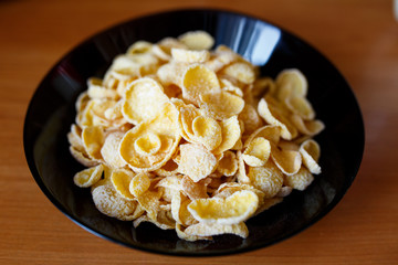 Cornflakes in a black bowl. Healthy food in the morning