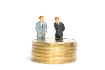 Miniature people: Businessman standing on stack of coin