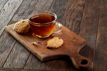Cup of tea with cookies on a cutting board on a wooden background, top view