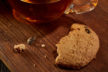 Cup of tea with cookies on a cutting board on a wooden background, top view