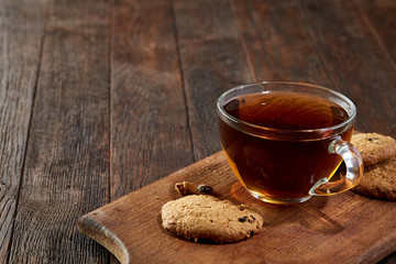 Cup of tea with cookies on a cutting board on a wooden background, top view