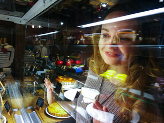 Женщина выбирает десерт в кондитерской.