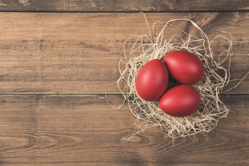 Red easter eggs in nest on wooden background  - 193276499
