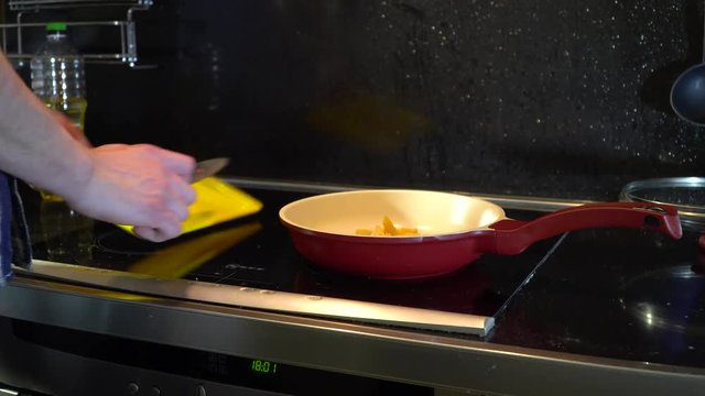man throws cheese from a cutting board into a frying pan