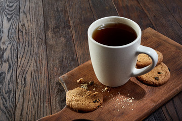 Cup of tea with cookies, workbook and a pencil on a wooden background, top view