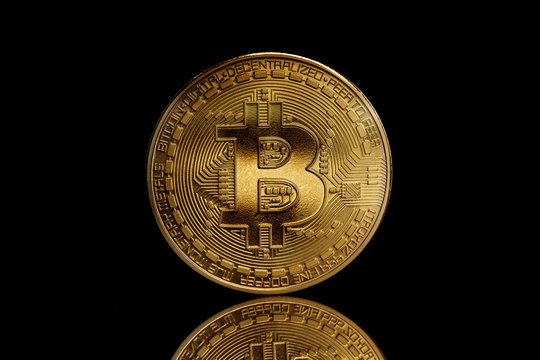 Close up of shiny golden Bitcoin cryptocurrency with black background 