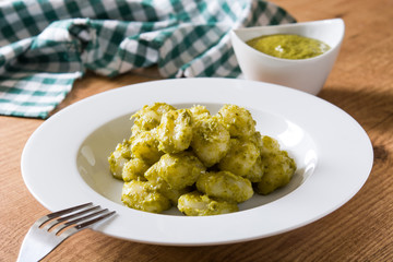 Gnocchi with pesto sauce in plate on wooden table