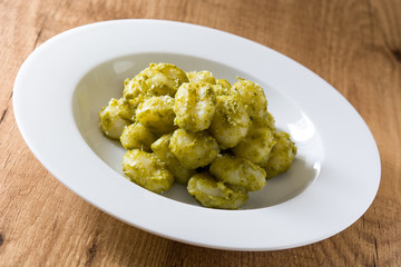 Gnocchi with pesto sauce in plate on wooden table