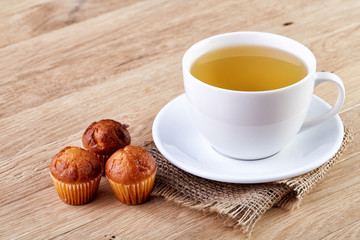 Cup of tea with cookies, workbook and a pencil on a wooden background, top view
