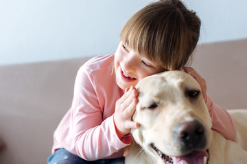 Kid with down syndrome hugging dog on sofa