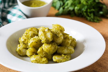 Gnocchi with pesto sauce in plate on wooden table